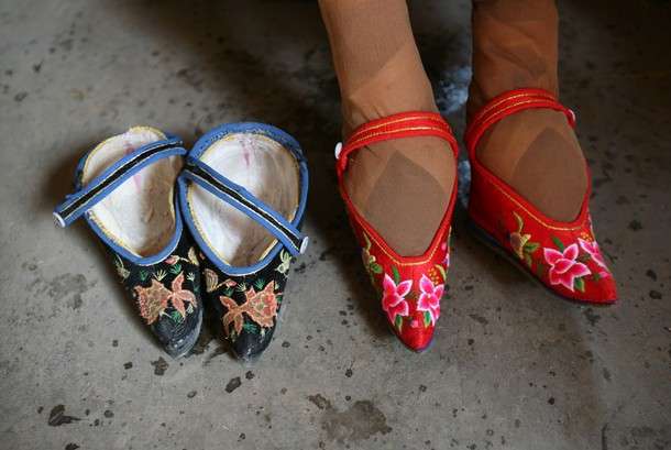 TONGHAI COUNTY, CHINA - APRIL 2: (CHINA OUT) 82-year-old bound feet woman Fu Jifen, displays "Three Cuns Golden Lotus" shoes she made at Liuyi Village on April 2, 2007 in Tonghai County of Yunnan Province, China. "Three Cuns Golden Lotus" is a term used to describe ancient Chinese women's bound feet, in which three "cuns" are about 3.39 inches. Liuyi Village is known as the "Bound Feet Women Village," where over 100 female senior citizens with bound feet and over the age of 70 live. The Chinese custom of foot binding under the feudalization, which started during the Tang Dynasty (AD 618-907) , was discontinued in the early 20th century. (Photo by China Photos/Getty Images)