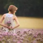 girl-with-flowers-standing-in-field-4k