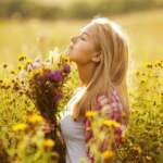 Beautiful blonde girl among the wildflowers in summer