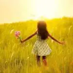 Little girl running on meadow with sunset