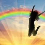 Happy woman jumping near rainbow