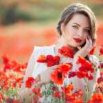 Pretty woman in field of poppy flowers, spring time