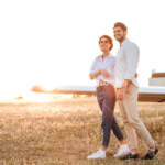 graphicstock-happy-couple-walking-together-across-the-field-with-airplane-on-background-at-sunset_HOXMqSdS3e_SB_PM