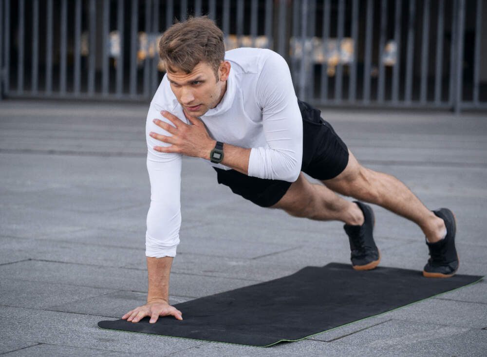мъж демонстрира упражнения за потупване на раменете с дъска за възстановяване на мускулната маса в ръцете ви